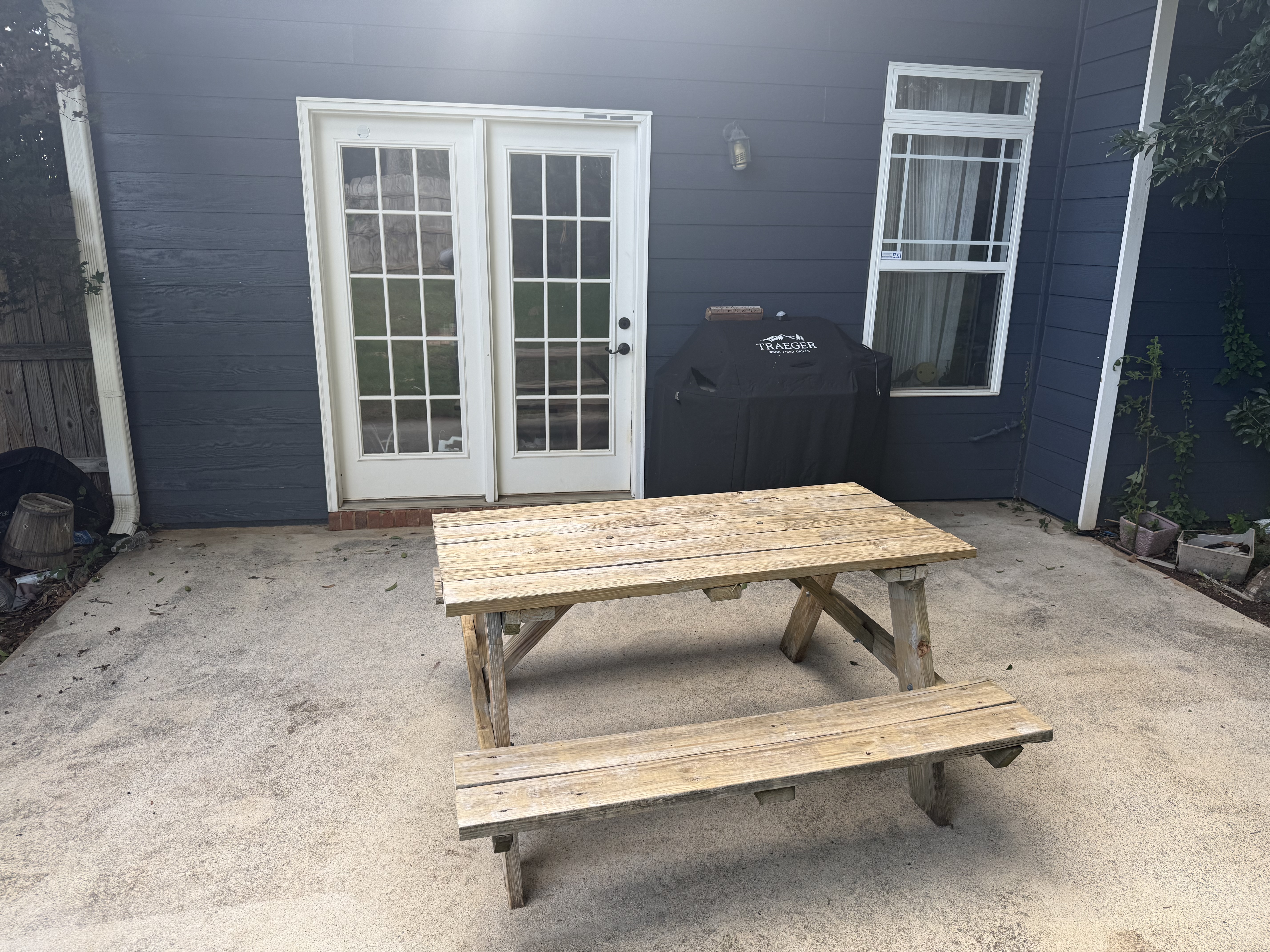 Concrete patio after — clean surface, brightened wood table